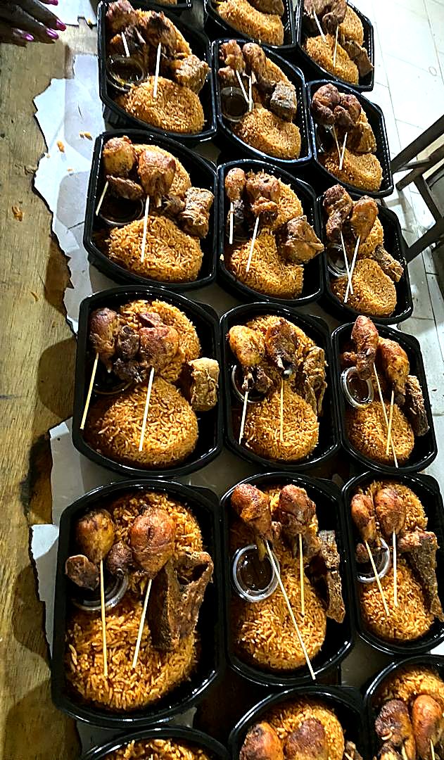 Rows of jollof rice meals with chicken and beef, packed for a large order.
