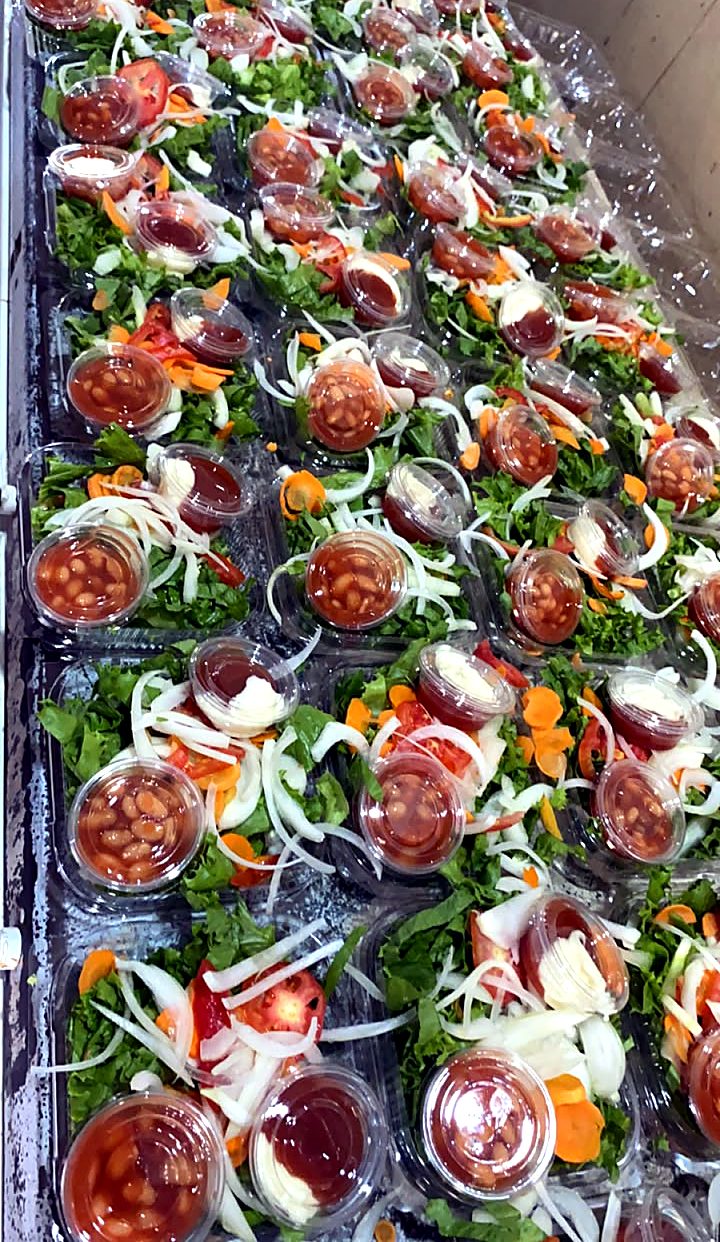 Dozens of salad packs with beans, tomato and sauce cups, prepared for an event.